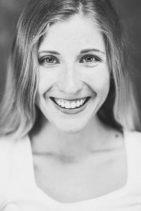 Das bin ich, die Betreiberin dieser Website. Frontales schwaz-weiß Portraitfoto. Junge Frau, dunkelblondes langes Haar, lächelnd.
